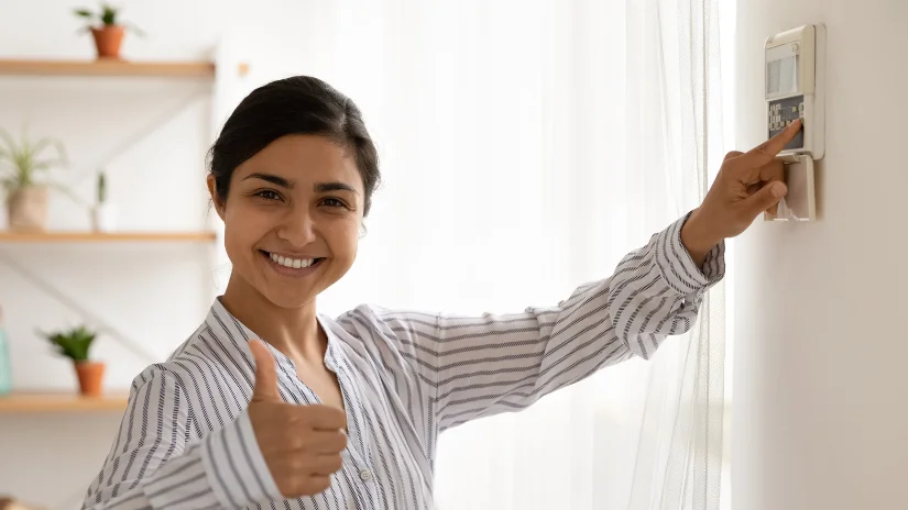 Woman showing thumbs up while setting ducted air conditioning at unit on the wall