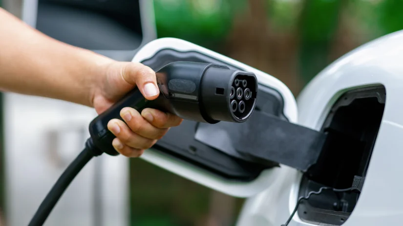 hand holding ev charger plugging into car
