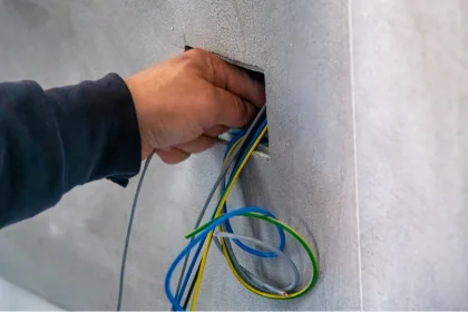 Hand of COYCO electrician reaching into wall cavity to finish wiring a home