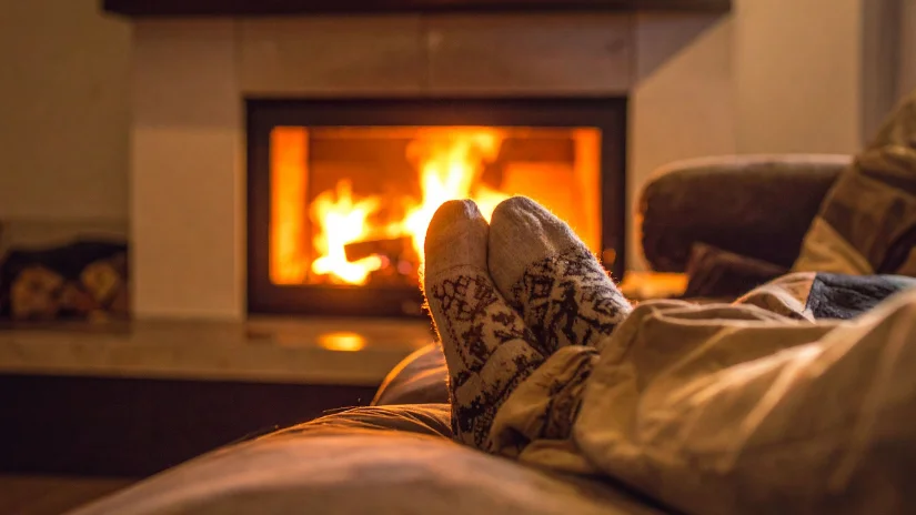 Relaxing by a wood heater fire showing legs with feet and socks on couch in front of a fire