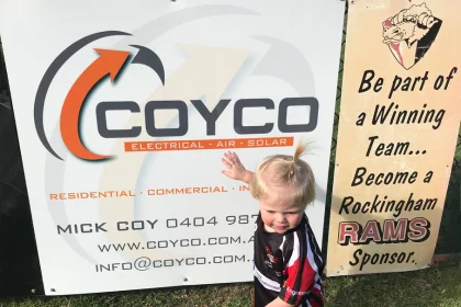Child standing in front of sponsorship board for COYCO and Rockingham Rams