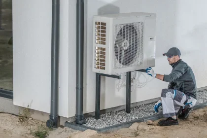 Electrician kneeling down at installation of Air Conditioning outside unit for COYCO Rockingham
