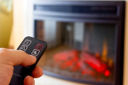 remote pointing at electric heater fireplace for warmth without effort